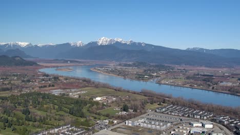 Aerial-View-of-River-Landscape-with-Mountain-Background---Sunny-Day