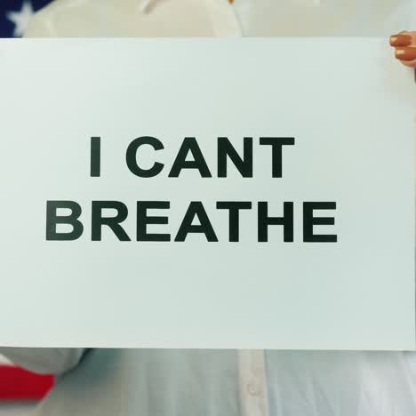 Woman-Holds-Poster-Stating-I-Cant-Breathe-On-American-Flag-Background