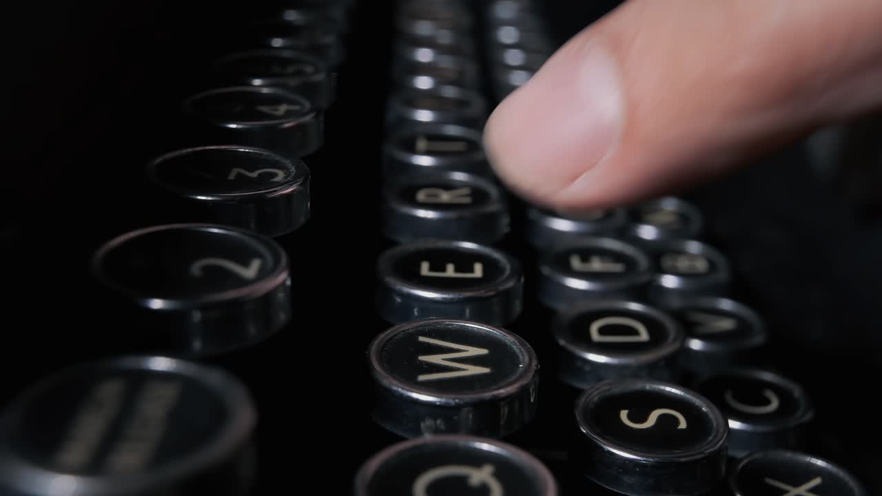 Fingers are pressing the keys of an old typewriter machine from the 1920s to write a document
