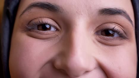 closeup macro portrait of young beautiful arabian female face with brown eyes looking straight at camera with positive smile