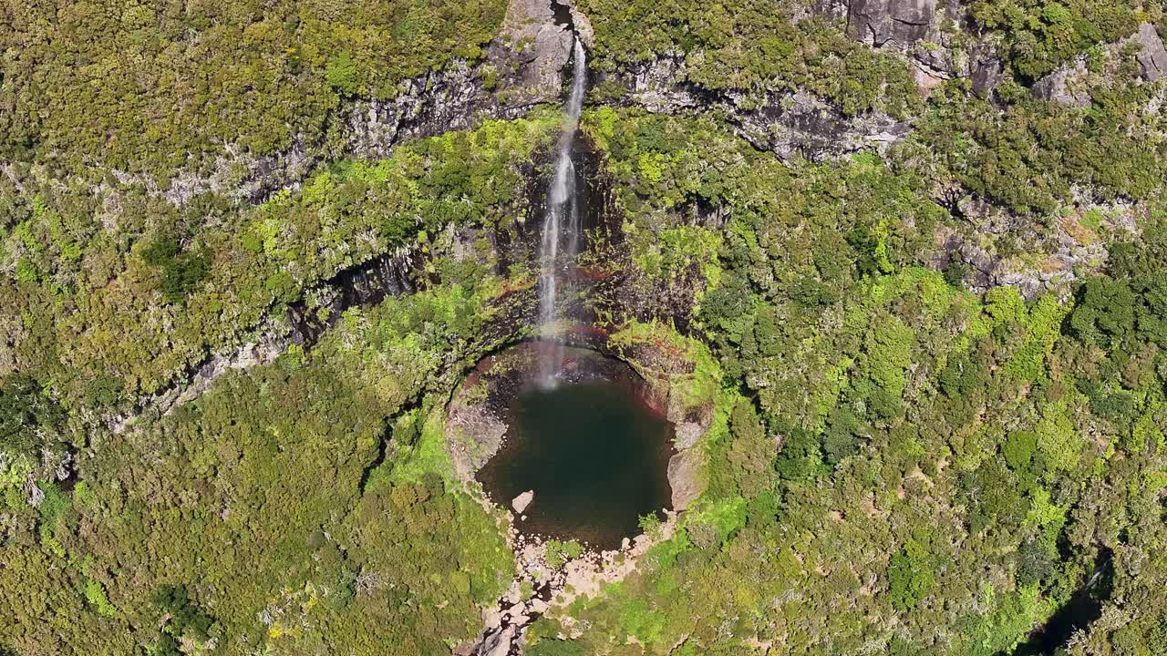 Drone view of person swimming in refreshing Risco waterfall pool, Madeira