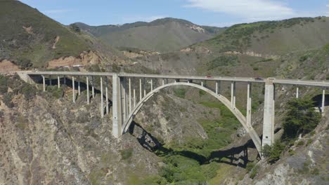 drone circles around bixby creek bridge to reveal beach and pacific ocean below