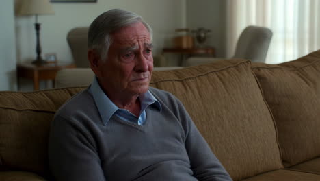 elderly man looking pensive while sitting on a couch