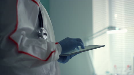 portrait doctor holding tablet computer in medical protective suit hospital ward