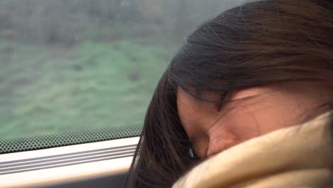 japanese girl in scarf sleeping against train window with scenery passing by