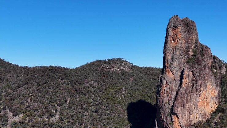 Campo lungo della formazione rocciosa The Breadknife sotto un cielo azzurro e limpido a Warrumbungle, Australia