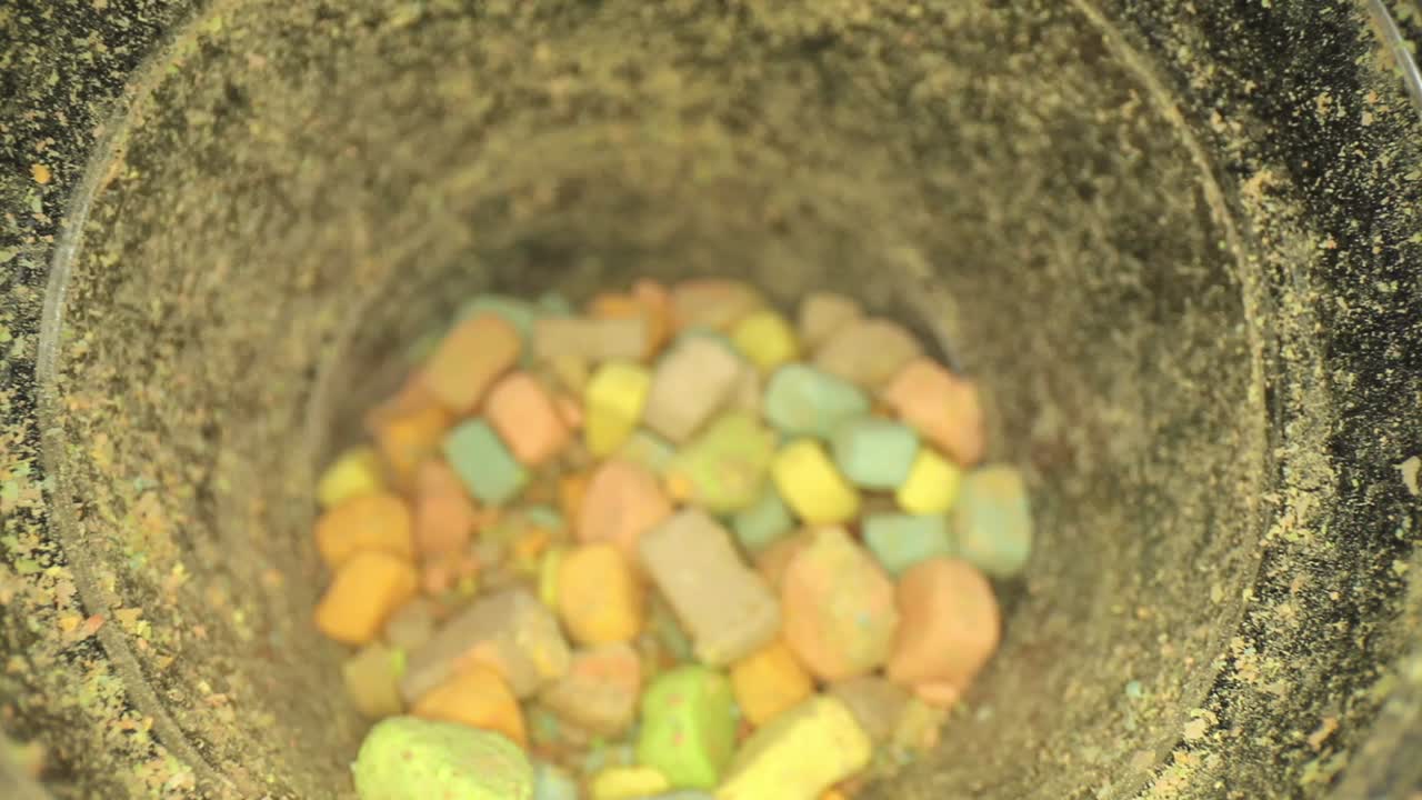 뚜껑 바깥쪽에서 시작하여 여러 색상의 마시멜로 조각이 담긴 용기의 바닥을 향해 밀어 넣습니다.