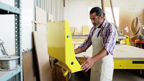 carpenter using his machine and smiling for camera