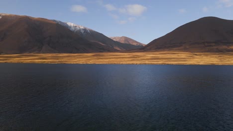 Slow-Aerial-dolly-in-flying-low-and-slow-over-beautiful-lake-towards-wavy-plains-and-rolling-mountains-of-New-Zealand