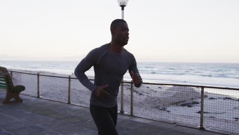 focused african american man exercising outdoors, running by seaside