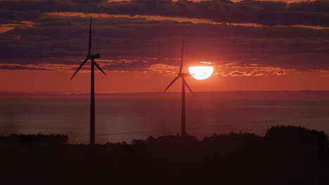 wind turbines silhouette producing green energy at red sunset