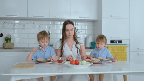 two little brothers with their mom make burgers laugh and smile together. happiness family in the kitchen