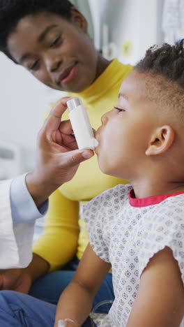 vertical video of african american male doctor examining child patient at hospital