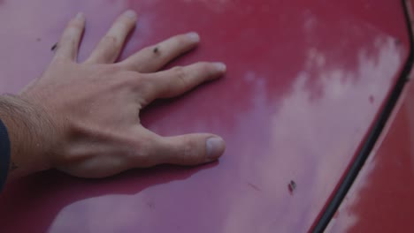 flies swarming around mans hand on red car hub