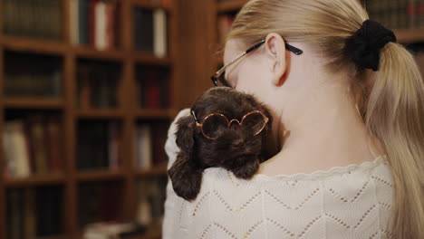 happy child in the library are a girl and a puppy with glasses. cute pets and education