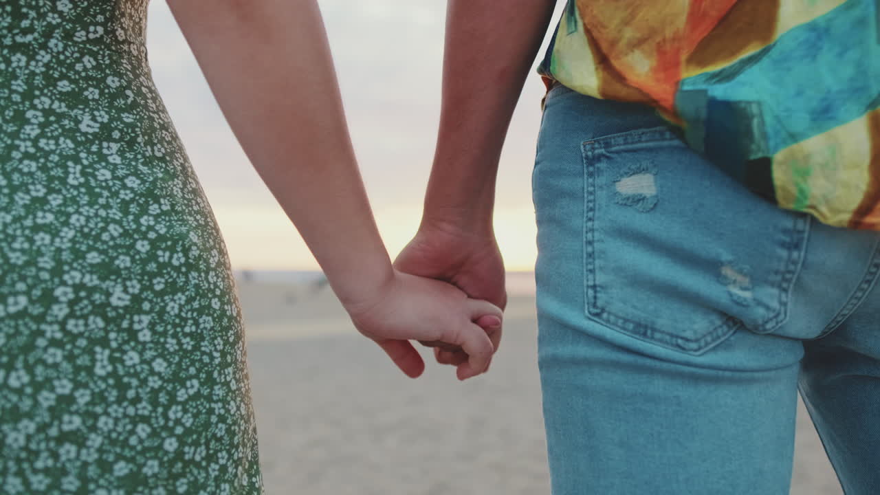 Una pareja de manos en la playa.