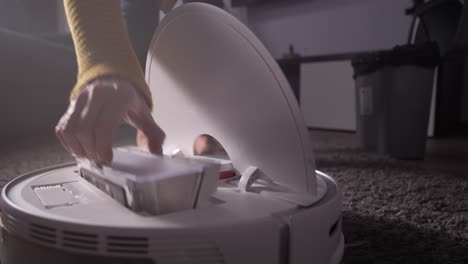 woman maintaining work of robotic hoover at home