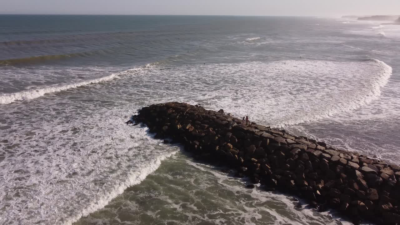 dos personas caminando en el rompeolas de la playa de chapadmalal en argentina