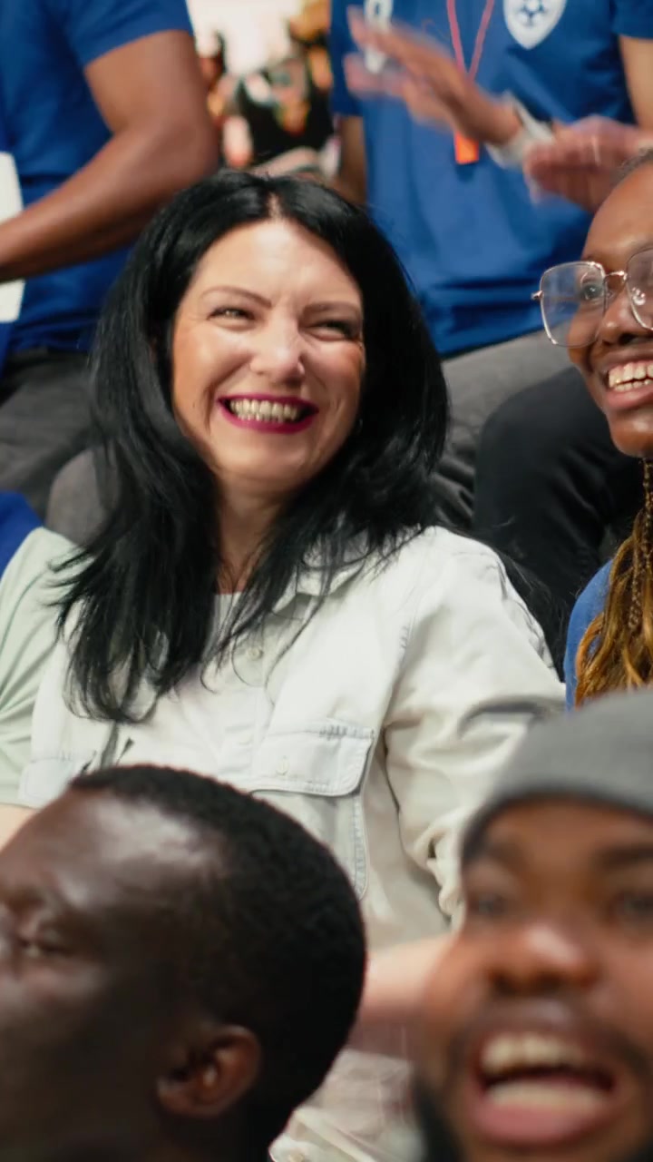 Vertical Video Soccer fans cheering and clapping during live football match in stadium stands