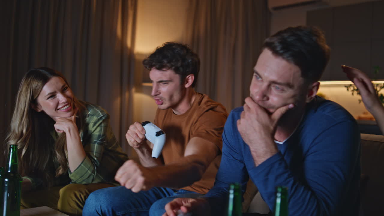 Video gamers have fun playing together at night home close up. Emotional guy