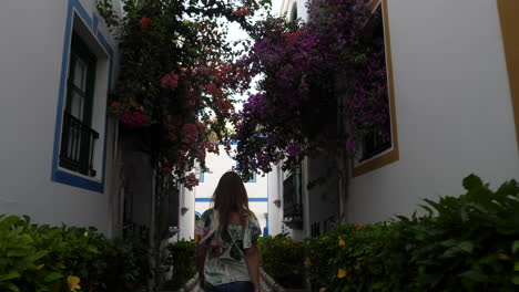 woman walks through the streets of puerto de mogan with beautiful buildings adorned with wonderful flowers and during sunset