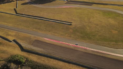 aerial drone tracking shot of racing car driving on track during competition