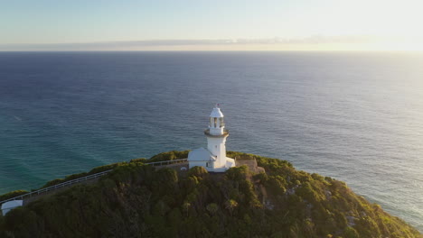 cinematic drone shot rotating around smoky cape lighthouse in australia with green island and the ledge in the background