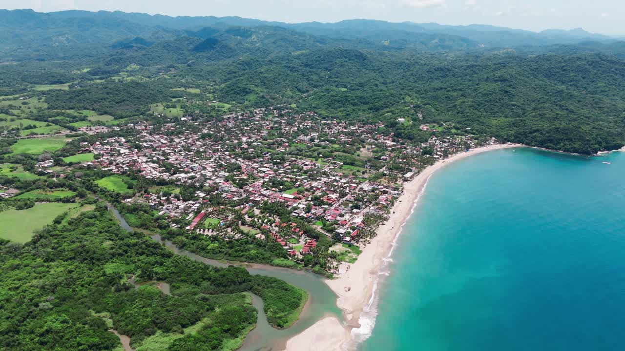 Aerial view of lo de marcos, a tropical beach town in nayarit, mexico, where a river meets the crystal-clear waters of the pacific ocean