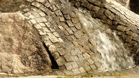 el agua fluye ondulando a través de un canal pavimentado en un patio de recreo para niños en un día soleado
