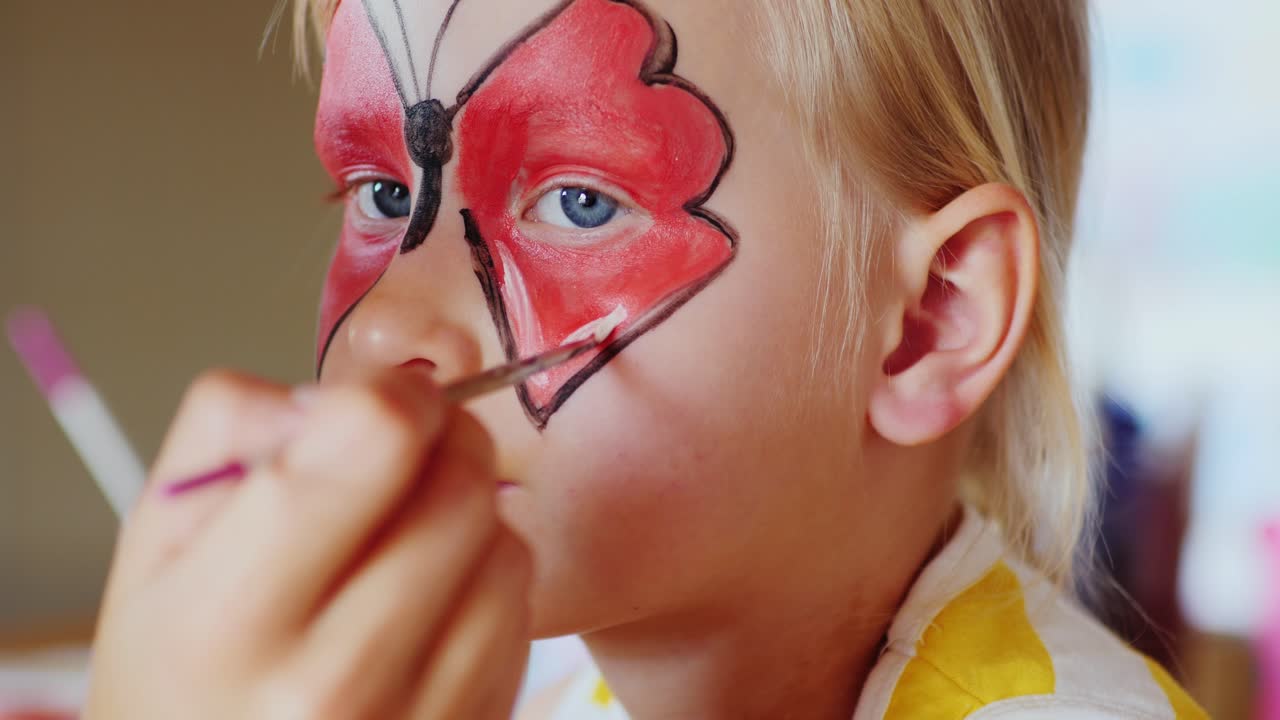 la niña aplicó un maquillaje festivo en forma de mariposas