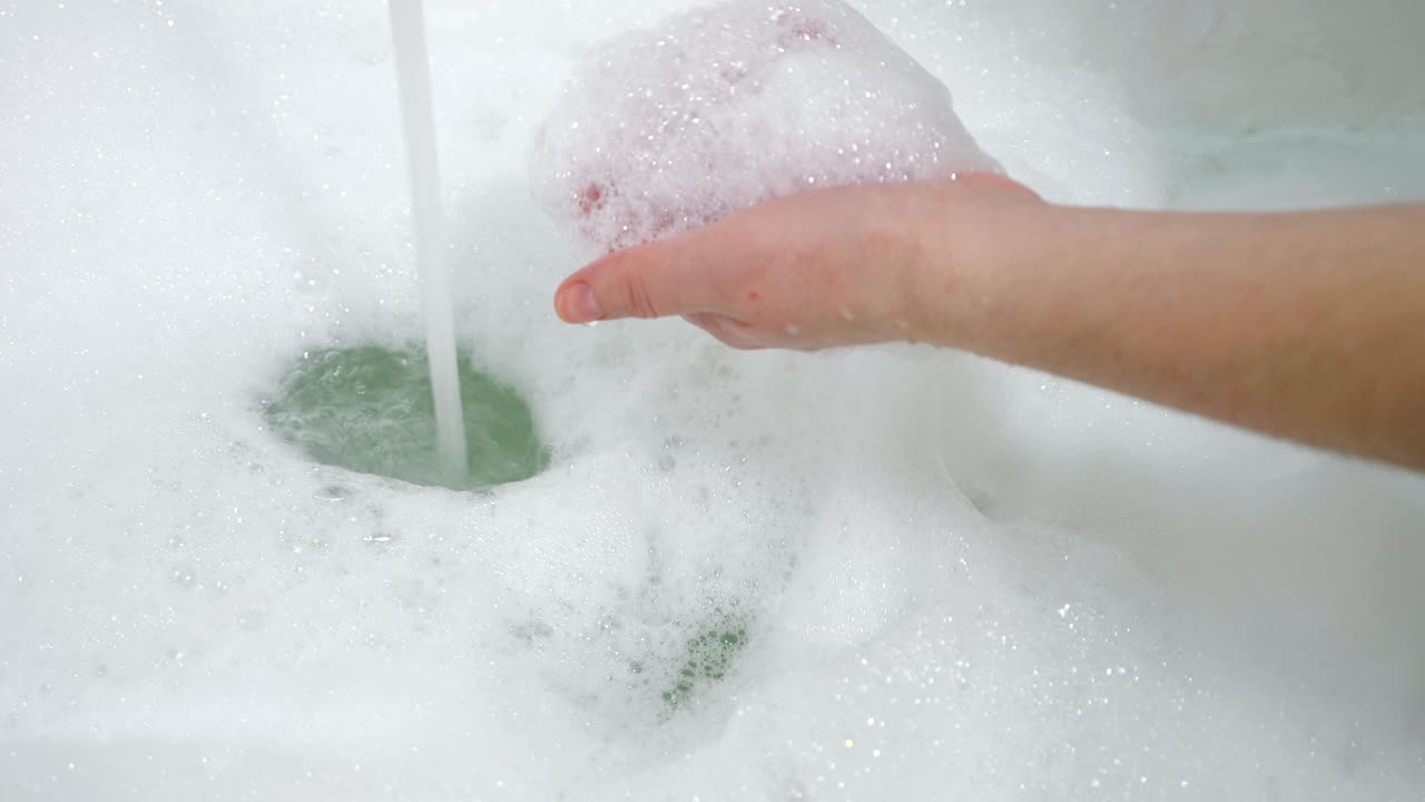 거품 욕조에 있는 소녀의 손
