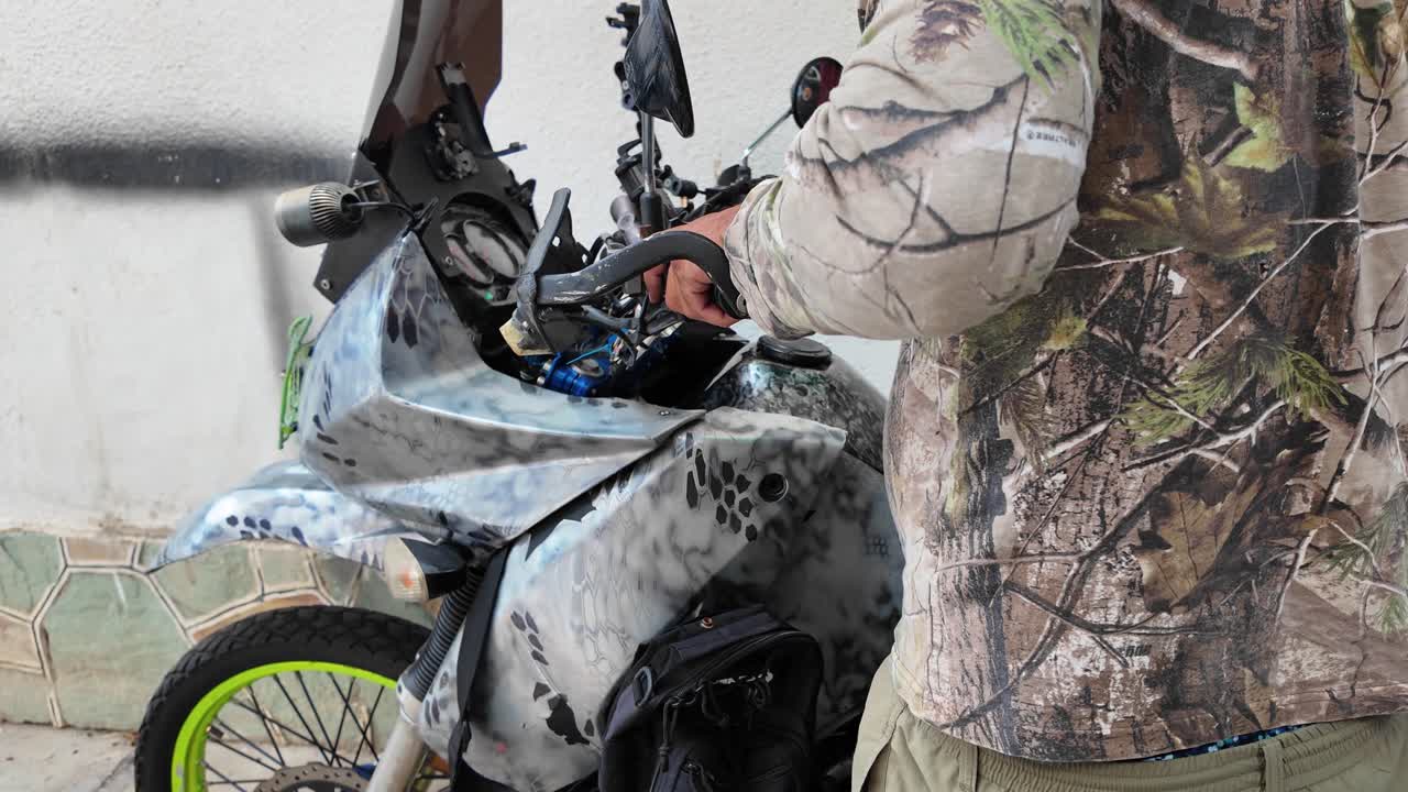 Handheld details manual work of an enthusiast checking the custom parts and controls of his personalized Off-Road Motorcycle