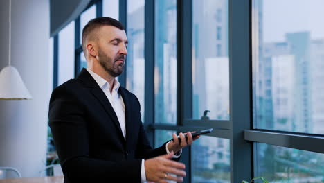 confident businessman answers the phone. man in suit has a short phone conversation standing near the window.