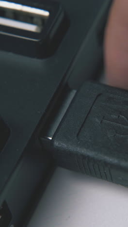 man takes off usb cable from black connecting hub by hand on white background extreme close view
