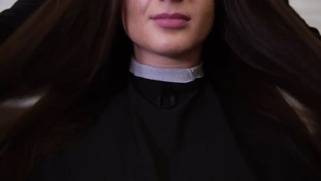 young woman looking to the camera after haircut. hairdresser waving clients long brown hair after haircut. cropped footage of a gorgeous brunette girl in barbershop. front view