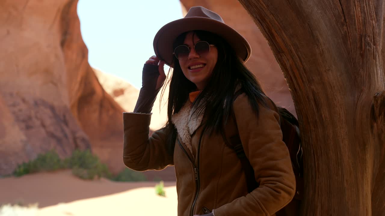 Donna esploratrice felice con cappello e occhiali da sole in un canyon nel deserto