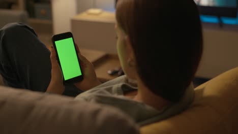 mujer sentada en un sofá y usando su teléfono inteligente