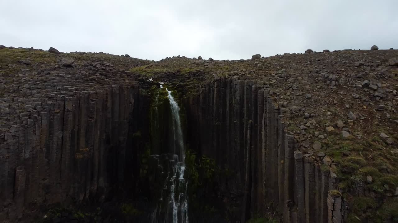 icónica cascada de stuðlafoss en islandia, drone aéreo vuela hacia atrás vista