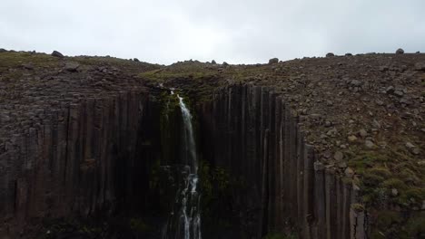 icónica cascada de stuðlafoss en islandia, drone aéreo vuela hacia atrás vista