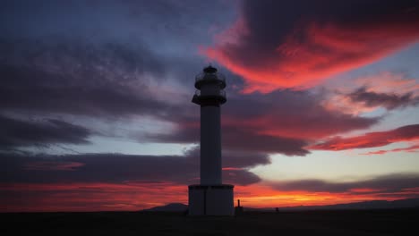 Faro-Cerca-De-La-Playa-Al-Atardecer-Bajo-Un-Cielo-Rojo