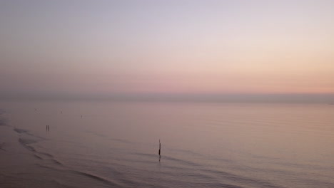 Toma-Aérea-De-Una-Tranquila-Playa-Del-Mar-Del-Norte-Durante-La-Puesta-De-Sol