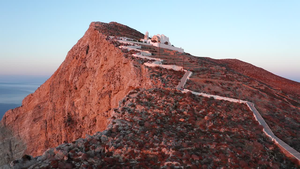 aéreo hacia la pintoresca iglesia de panagia en la cima de una colina, con hermosas luces de puesta de sol, isla de folegandros
