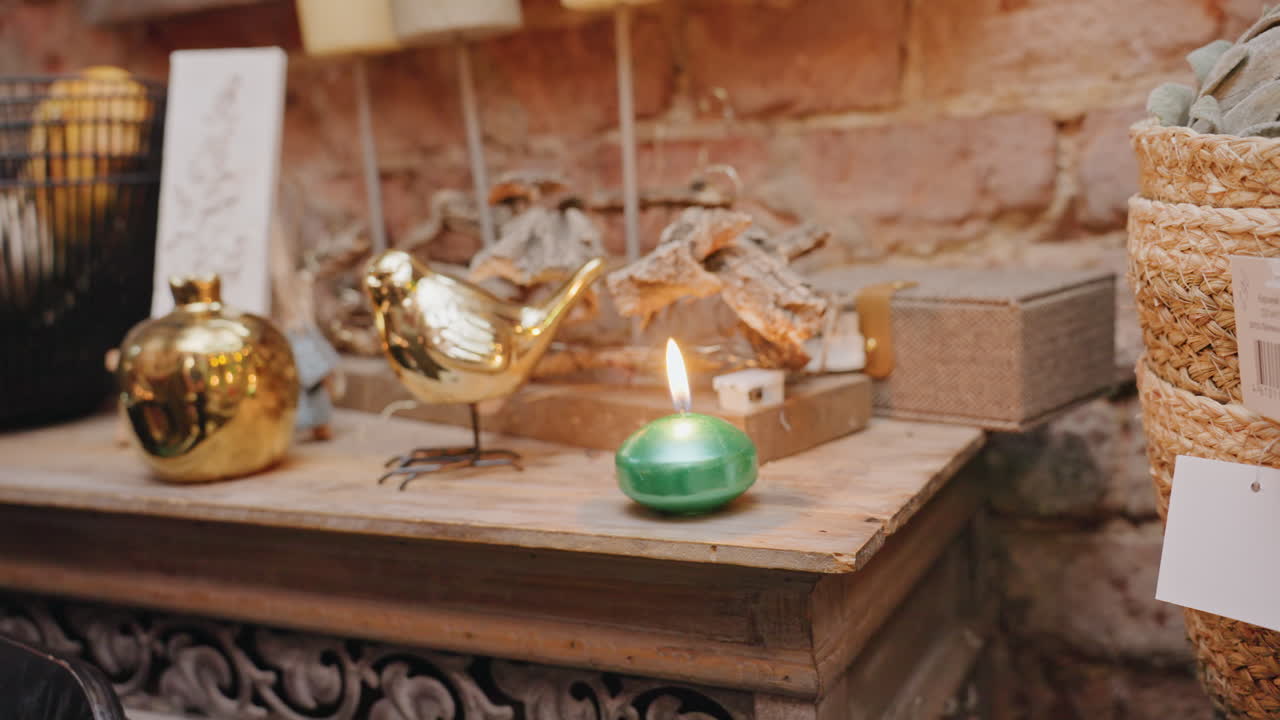 Caucasian florist lighting votive candle mantel, hand reaches for match then tealight ignites, brass ornament and driftwood vignette on wooden shelf, brick backdrop, warm glow casting soft shadows