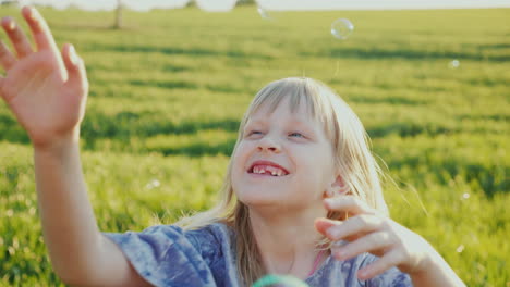 Una-Niña-Alegre-Atrapa-Pompas-De-Jabón-Se-Le-Cayeron-Los-Dientes-De-Leche-4k-Video-En-Cámara-Lenta