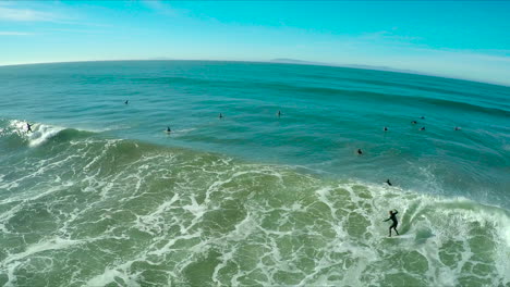 Aerial over surfers riding waves on a Southern California beach 1