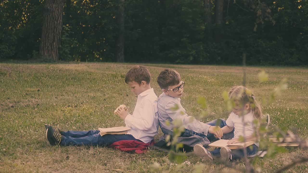 학교 유니폼을 입은 소년들이 책을 가진 금발 소녀  ⁇ 에 앉아 있습니다.