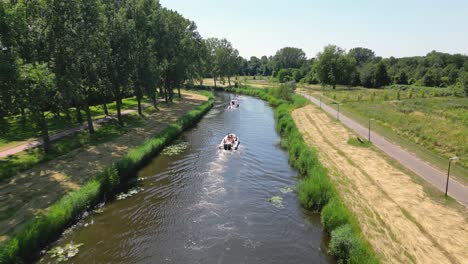 Aerial-drone-shot-above-a-nature-park,-water-canal-with-boats,-of-Almere-city,-province-Flevoland,-Netherlands