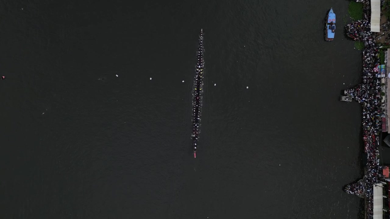 Vibrant cultural scene showing the annual Vallam Kali (boat race) in Kerala, India. Dozens of rowers chant and paddle a traditional wooden snake boat through the backwaters, showcasing India's rich he