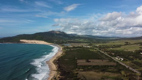 Interstate-highway-road-and-blue-coastline-with-buildings-nearby,-aerial-view