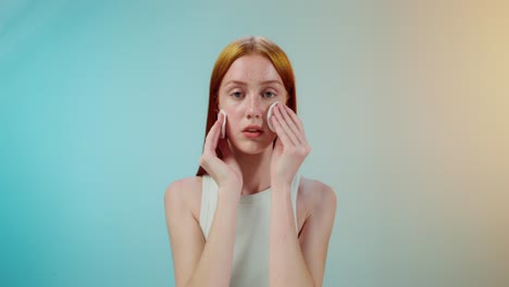 woman cleansing her face with cotton pads